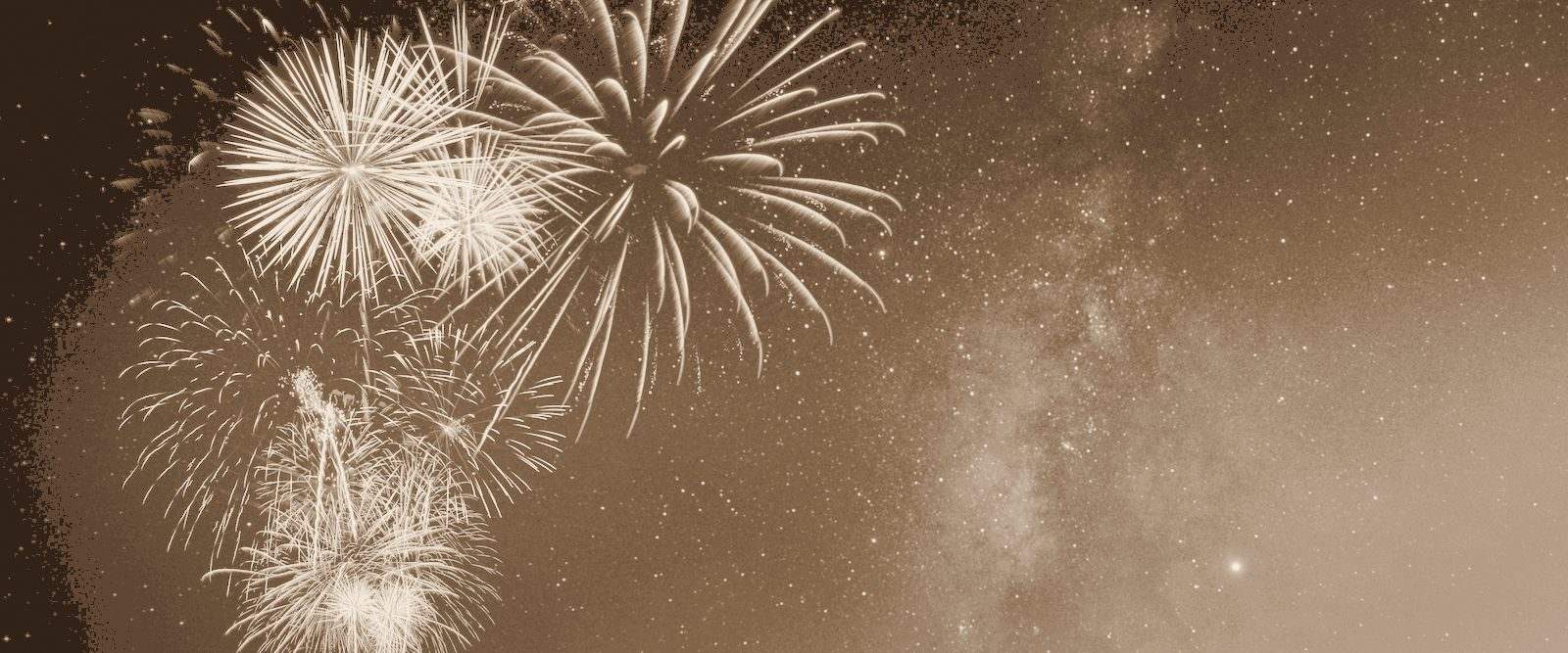 Fireworks over a dark sky, in warm bronze