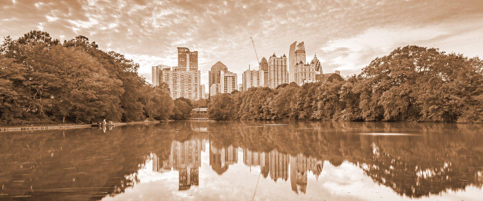The Atlanta skyline reflected in the lake at Piedmont Park at dusk, in warm bronze