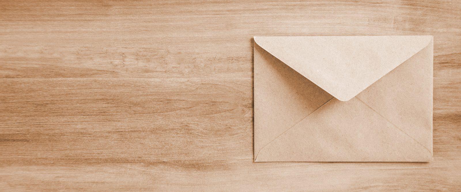 A single kraft envelope resting on a wooden table, in warm bronze